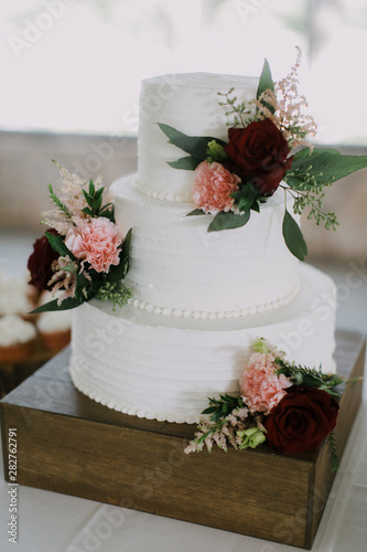 Modern White Wedding Cake with pink and red roses, stacked cake with vanilla icing, wedding reception 