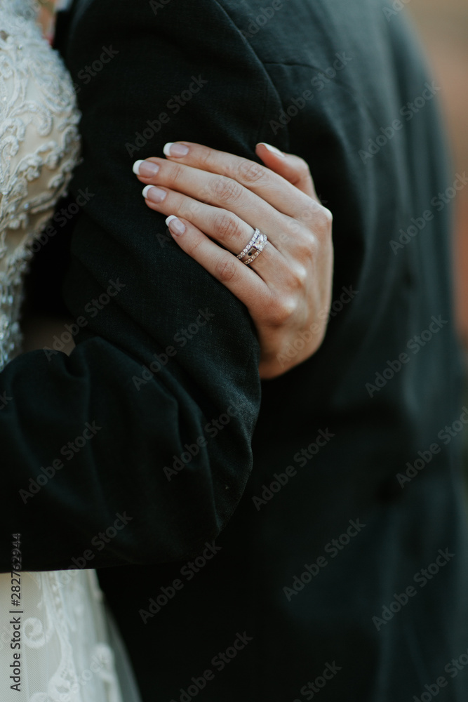 Bride holding Groom, closeup shot of wedding ring, diamond ring on bride's hand