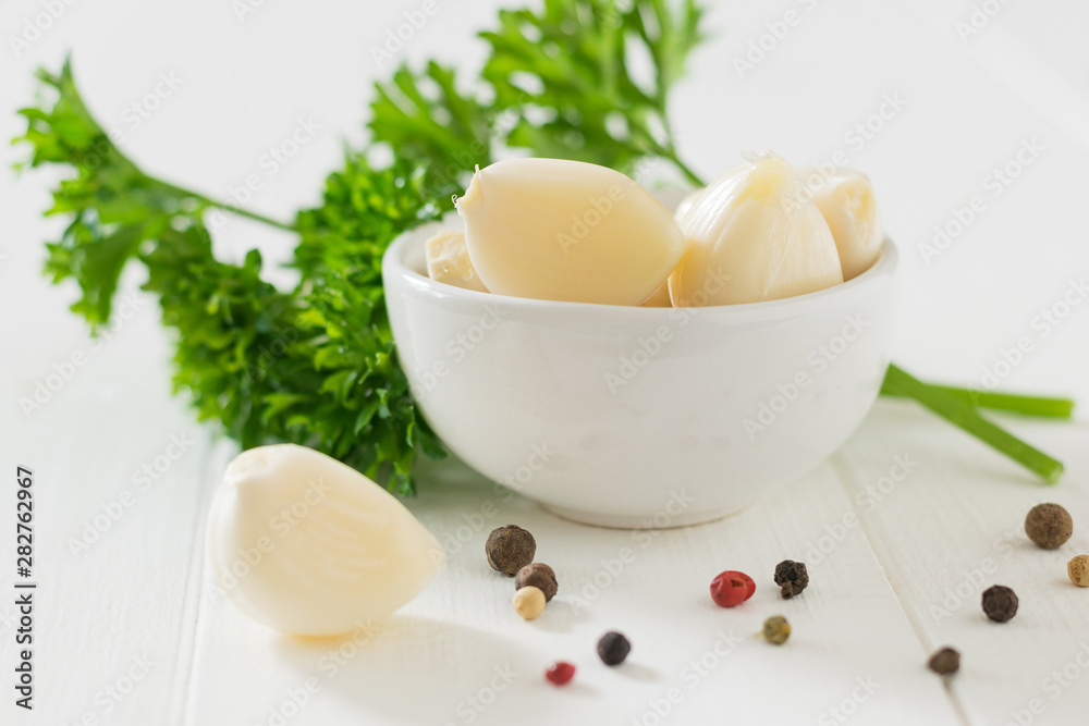 Peeled garlic with herbs and pepper on a white table. Component of traditional medicine. Peeled garlic with herbs and pepper on a white table. Component of traditional medicine.