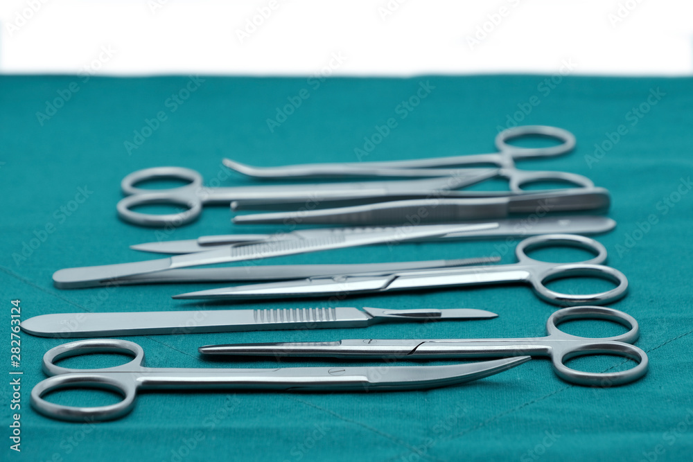 Basic surgical instrument scalpel forceps tweezers scissors on surgical green drape fabric with copy space text Basic surgical instrument scalpel forceps tweezers scissors on surgical green drape fabric with copy space text