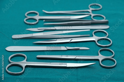 Basic surgical instrument scalpel forceps tweezers scissors on surgical green drape fabric