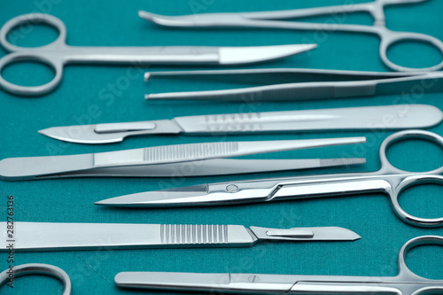 Basic surgical instrument scalpel forceps tweezers scissors on surgical green drape fabric