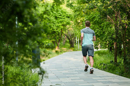 Man is jogging in the park on green background