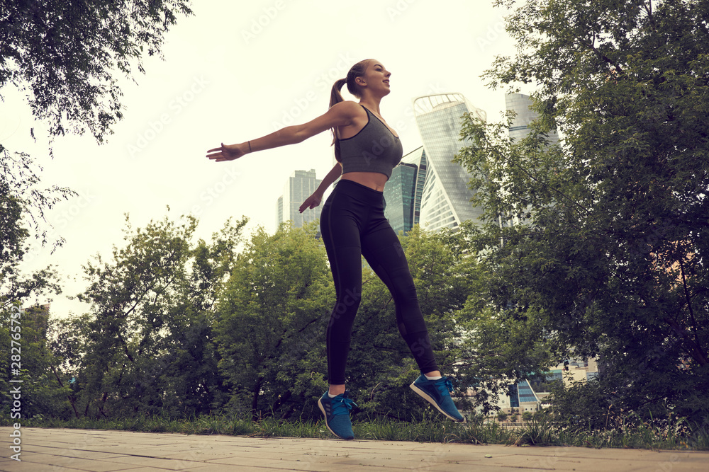 Fit athletic woman runner performing a big leap outdoors