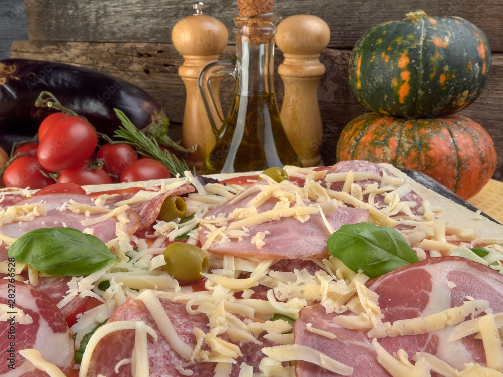 Pizza on thin dough.With slices of salami and ham ,olives and tomatoes. Pizza on thin dough.With slices of salami and ham ,olives and tomatoes.