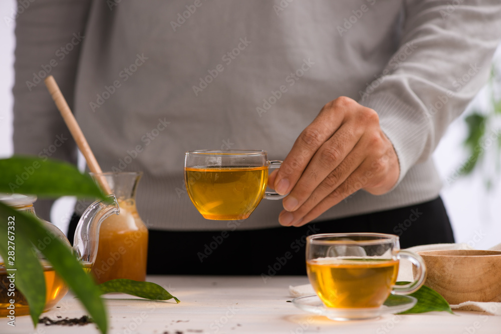 Male hands holding cup of tea glass on light background Male hands holding cup of tea glass on light background