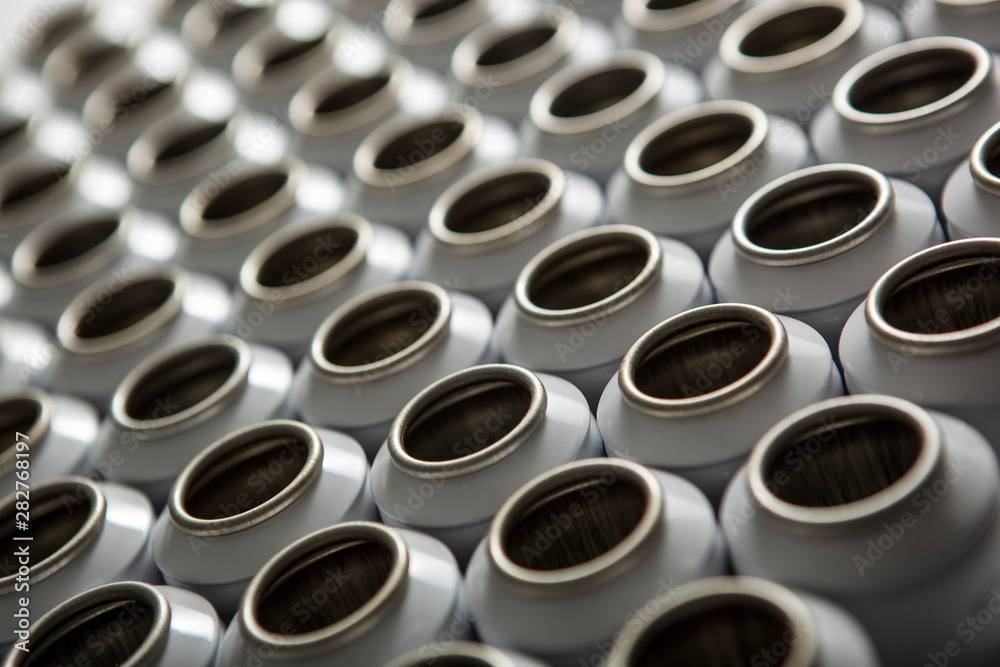 Numerous white aluminum aerosol cans against a white background. the boxes are in the raw form and in a row in a row. Numerous white aluminum aerosol cans against a white background. the boxes are in the raw form and in a row in a row.