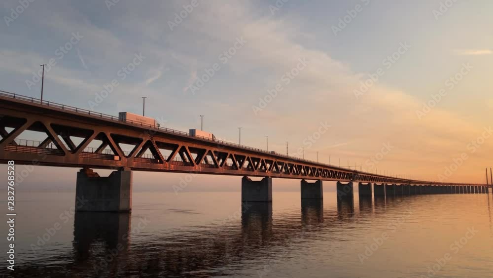 Still shot of a beautiful bridge at sunset connecting Sweden and Denmark providing a tansport route for trucks Still shot of a beautiful bridge at sunset connecting Sweden and Denmark providing a tansport route for trucks