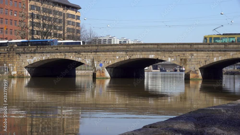 Old stone arch bridge in Helsinki with traffic and reflections on the water Old stone arch bridge in Helsinki with traffic and reflections on the water