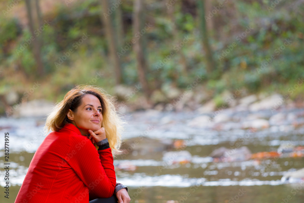 Beautiful young woman enjoying autumn by the side of a wild lake Beautiful young woman enjoying autumn by the side of a wild lake