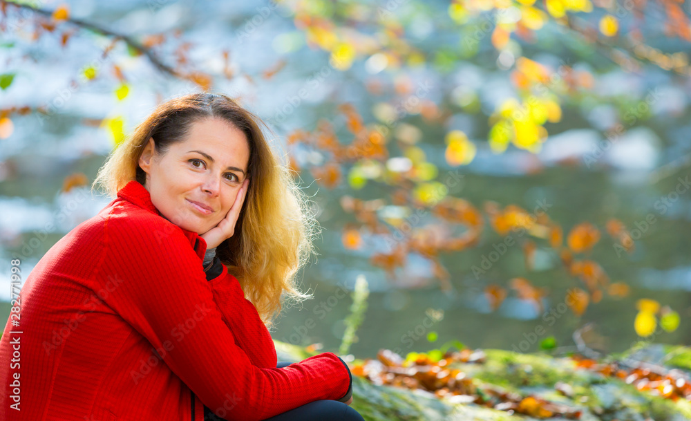 Beautiful young woman enjoying autumn by the side of a wild lake Beautiful young woman enjoying autumn by the side of a wild lake