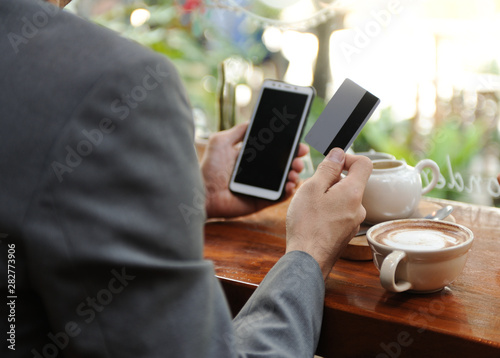 Business man using smartphone for shopping online while drinking some coffee,Business man using net banking in smartphone,Selective focus