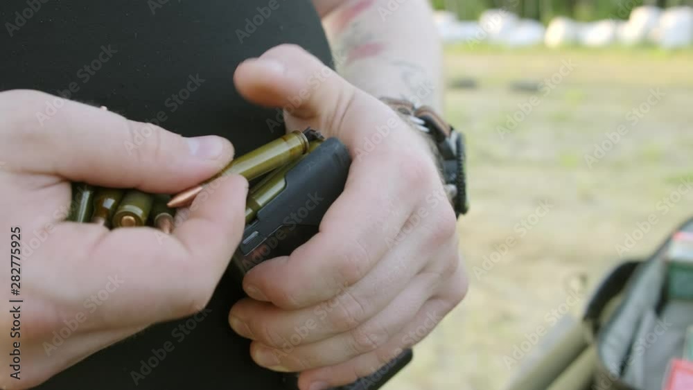 Handgun Loading man's hands loading a pistol magazine. man loads the clip of pistol ...