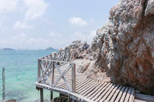 wooden walkway bridge on rock  over the blue ocean on the sunny day