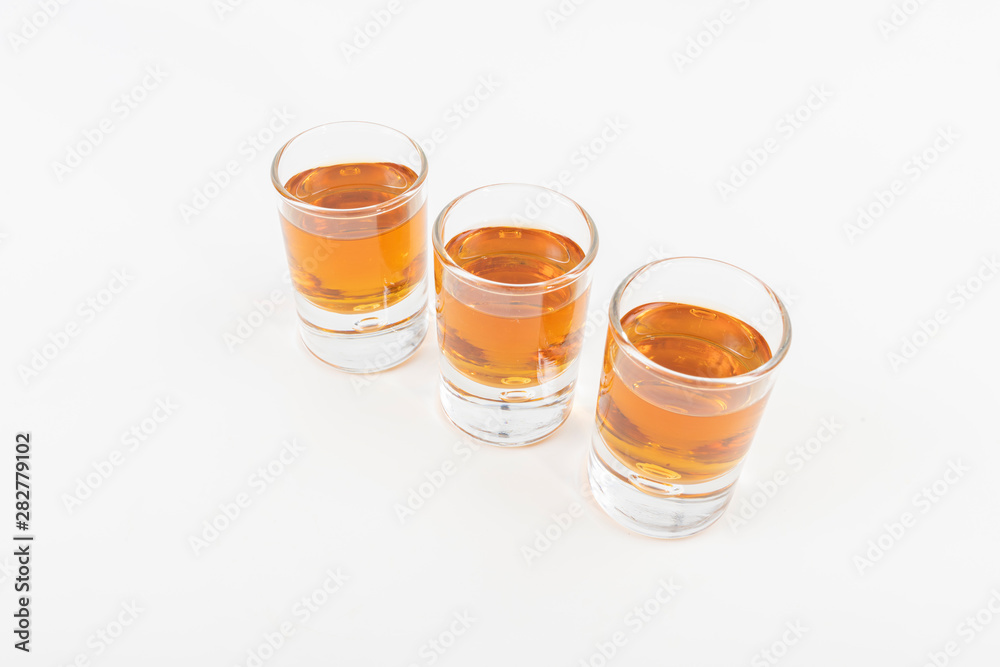 Delicious and luxurious whiskey served in three glasses lined up and isolated on a white background Delicious and luxurious whiskey served in three glasses lined up and isolated on a white background