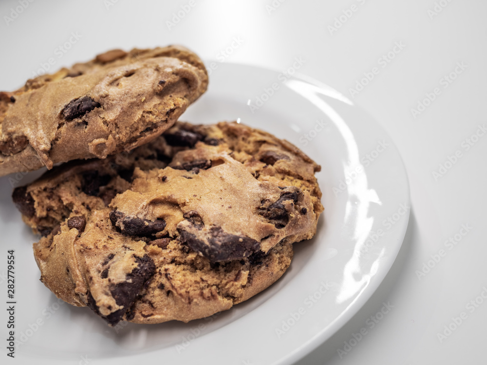 Closeup shot of two pieces of chocolate cookie on white plate and white table. Closeup shot of two pieces of chocolate cookie on white plate and white table.