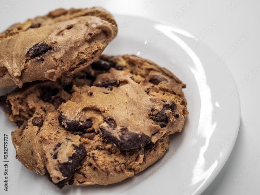 Closeup shot of two pieces of chocolate cookie on white plate and white table. Closeup shot of two pieces of chocolate cookie on white plate and white table.
