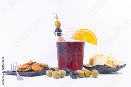 Spanish tapas style. A Very fresh vermouth, olives, black olives potato chips and mussels in a black slate. White background