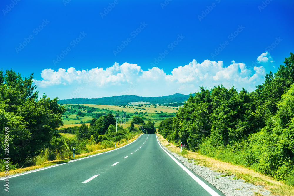 Fototapeta premium Scenic road in the region of Lika in Croatia, cloudy sky and mountains in background