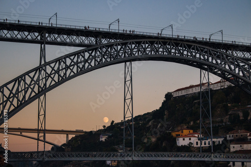 Porto, Portugal - 10/20/2019: Famous Porto bridge Ponte Luis in the evening bottom view. Porto bridge in twilight with moon on background. Portuguese river Douro with metro bridge in evening dusk. 