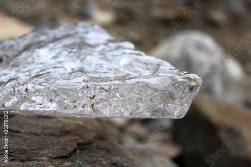 a piece of ice on the background of stones