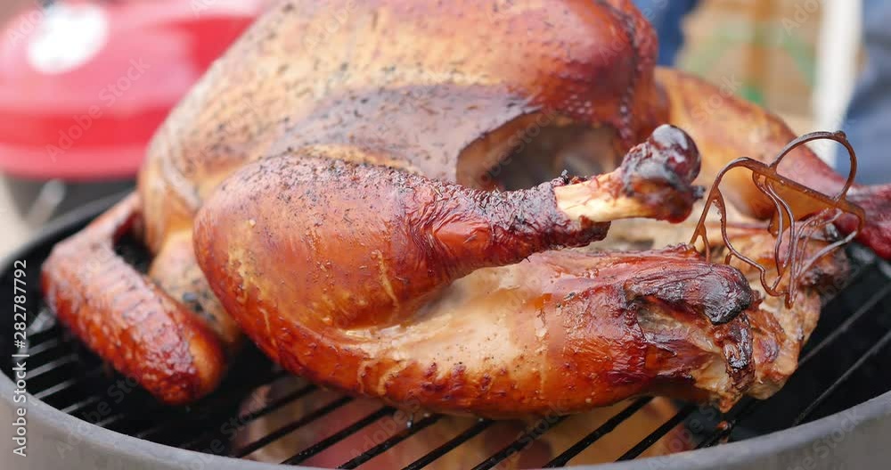 Close-up of delicious looking turkey cooking on a small smoker, steaming and dripping juices