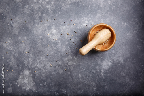 White peppercorns in a mortar for spices. Wooden mortar and pestle full with white pepper on gray background. Top view. Copy space.