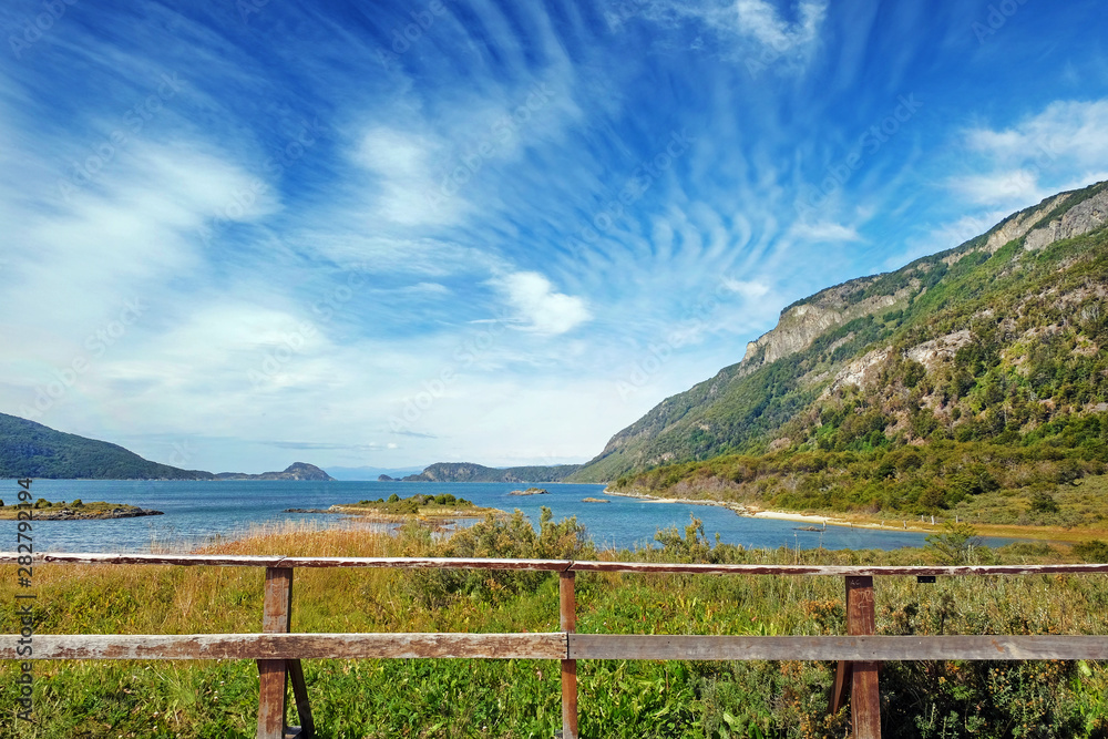 Panoramic view of Tierra del Fuego National Park, showing small islands surrounded by green vegetation and water, against a blue sky.