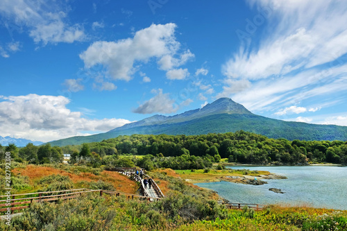 Panoramic view of Tierra del Fuego National Park, showing a volcano surrounded by green vegetation and water, against a blue sky. photo