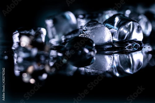 pile of different ice cubes on reflection table on black background 