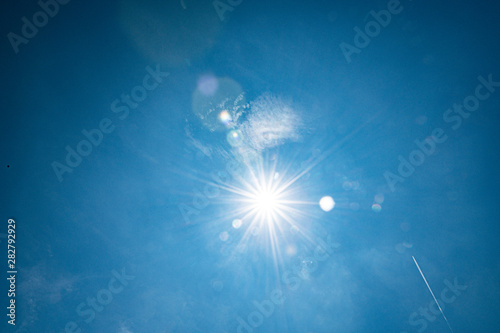sun star creates flare on a blue summer sky photo
