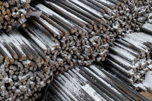 Steel snow covered reinforcement bars at the outdoor warehouse, industrial background, building armature