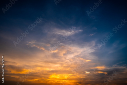Twilight dramatic blue sky with white fluffy clouds and bright orange sunlight. © rivermartin