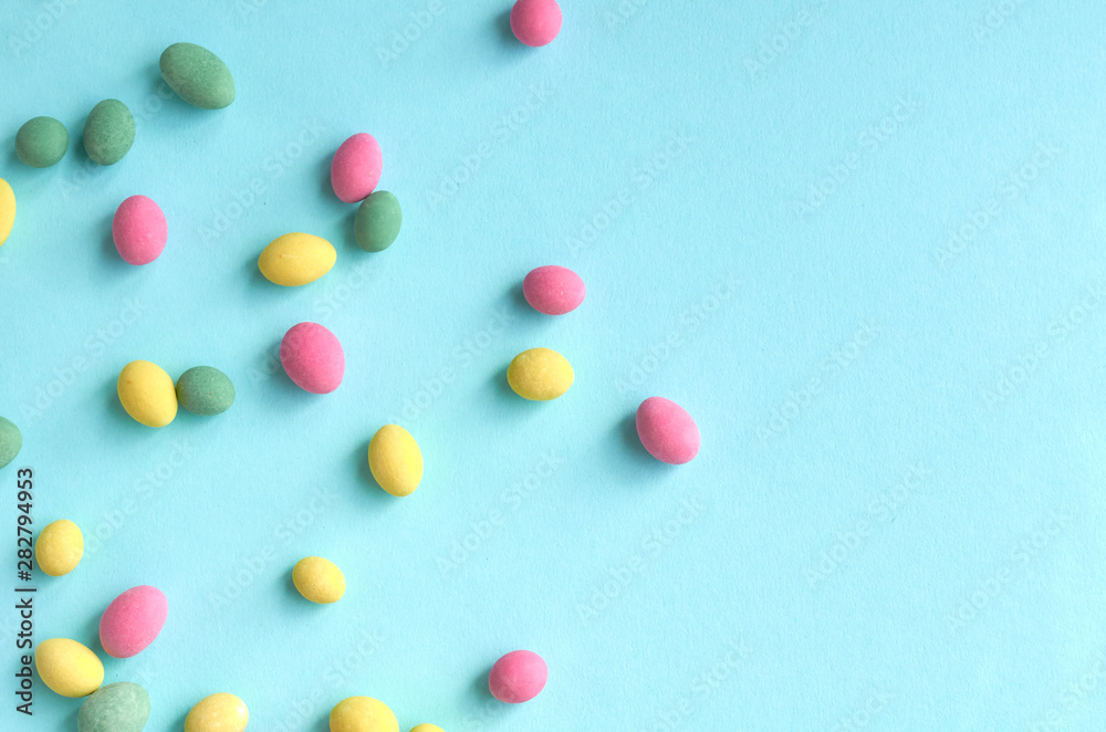 Colored sweets, peanut covered with glaze on blue background composition.
