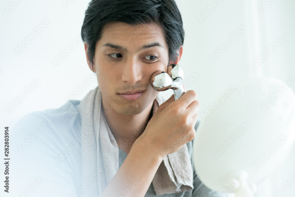 美顔ローラーでマッサージをする男性