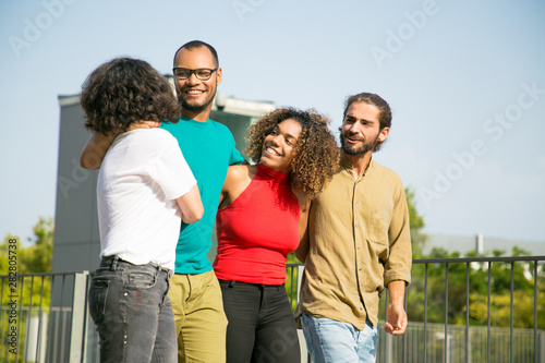 Happy multiethnic friends enjoying walking outdoors. Mix raced group of people walking outside, hugging each other, talking and laughing. Friendship and lifestyle concept