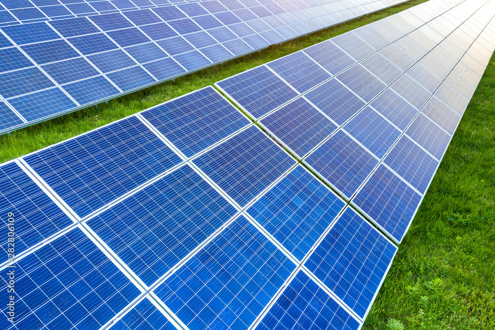 Surface of solar photo voltaic panels system producing renewable clean energy on green grass background.