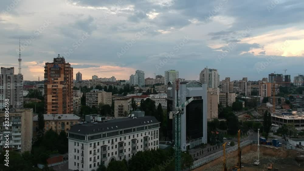 A calm flight over a European city of Kyiv, Ukraine. Construction of a shopping center. Drone flying sideways very slowly. tower crane, tv tower A calm flight over a European city of Kyiv, Ukraine. Construction of a shopping center. Drone flying sideways very slowly. tower crane, tv tower