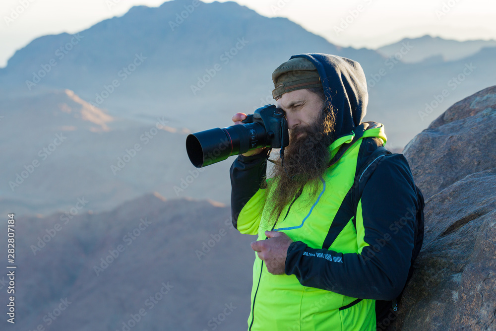 A bearded man on the mountain of Moses with a camera, pilgrimage to the holy places. Nature photographer taking photos in the mountains.