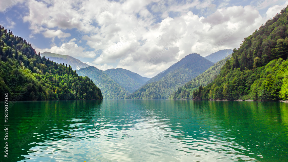 Natural landscape. Panorama view of the lake Small Ritsa. Trees reflecting in the blue from lapis lazuli water. Ritsa National Park, Abkhazia