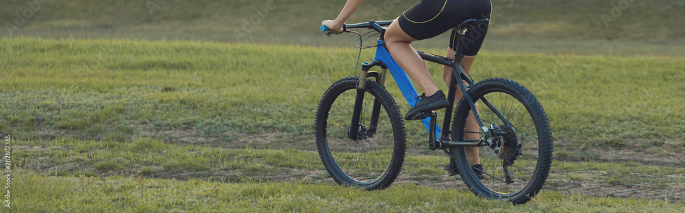 A girl riding a mountain bike on an asphalt road, beautiful portrait of a cyclist at sunset	