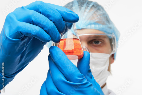Laboratorian eximining test tube with orange liquid photo