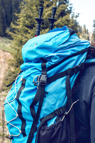 Man hiking in mountains with big red travel backpack. Traveler male in green hat trekking during his journey. Travel, people, sport and healthy lifestyle concept
