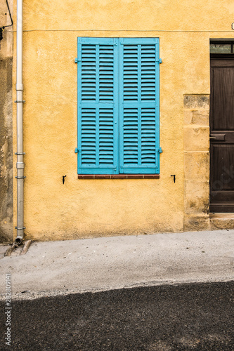 Closed blue shutters on a vintage yellow wall in a street in France