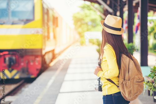 Cheap Travel and Lifestyle concept.Holiday Time,Young Traveler woman wearing sneaker and standing at train station.Asian Backpacker waiting train alone and plan trip in summer time.