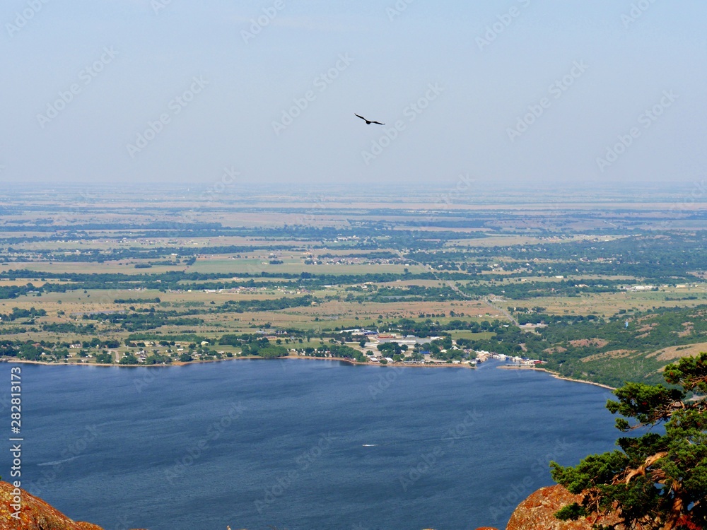Obraz premium Aerial view of Lake Lawtonka, seen from the peak of Mt. Scott, Oklahoma, USA, with a bird flying in the skies.