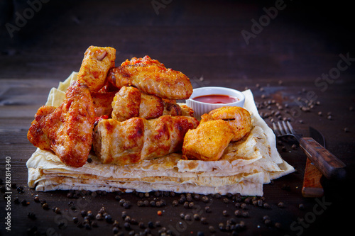 Assorted pieces of fried chicken. Grill dishes for the restaurant menu. Wooden background.