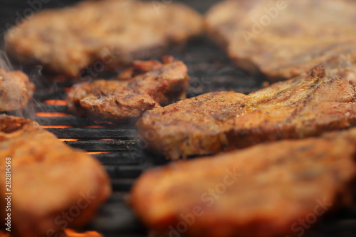closeup on crispy grilled meat on smoking hot cast-iron grate with flames underneath- realistic food and barbecue party concept - foreground and background blanked out blurry