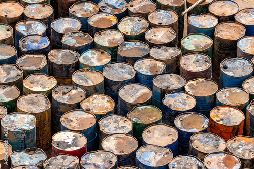 Dirty rusty abandoned oil drums all banged up and with signs of leakage