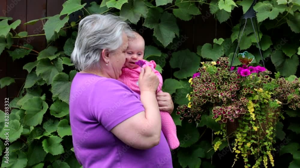 Happy and Beautiful Grandmother with short Silver Hair playing in the Garden with her 4 Month Old Cute Granddaughter. Happy Family Concept Happy and Beautiful Grandmother with short Silver Hair playing in the Garden with her 4 Month Old Cute Granddaughter. Happy Family Concept